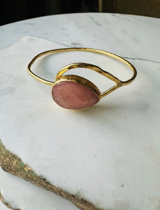 Gold-plated artisanal bracelet with peach moonstone on a marble surface