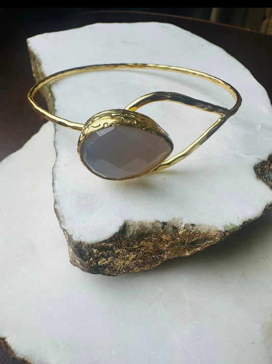 Gold-plated snow Quartz teardrop bracelet with a stone on a white rock