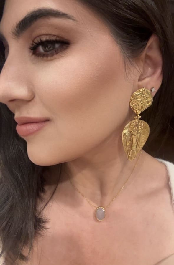 Model looking down wearing artisanal sustainable hieroglyphics statement dangle earrings