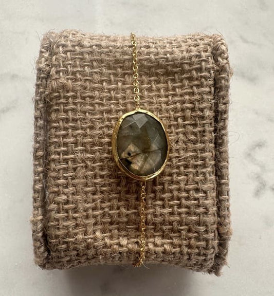 Gold minimal labradorite bracelet on a textured beige fabric background