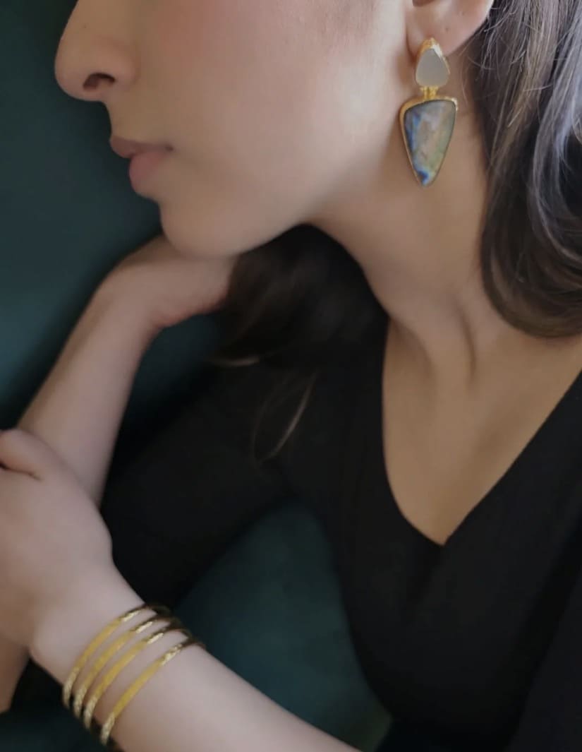 Profile of model wearing artisanal bold earrings and gold-plated bangles