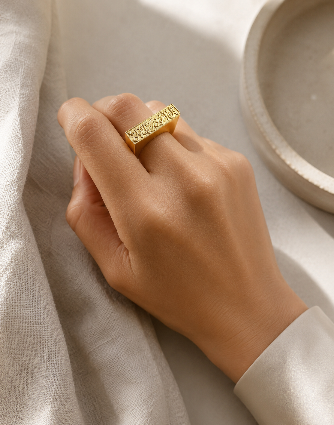 21K gold-plated contemporary handmade Qul bar ring on hand against neutral backdrop