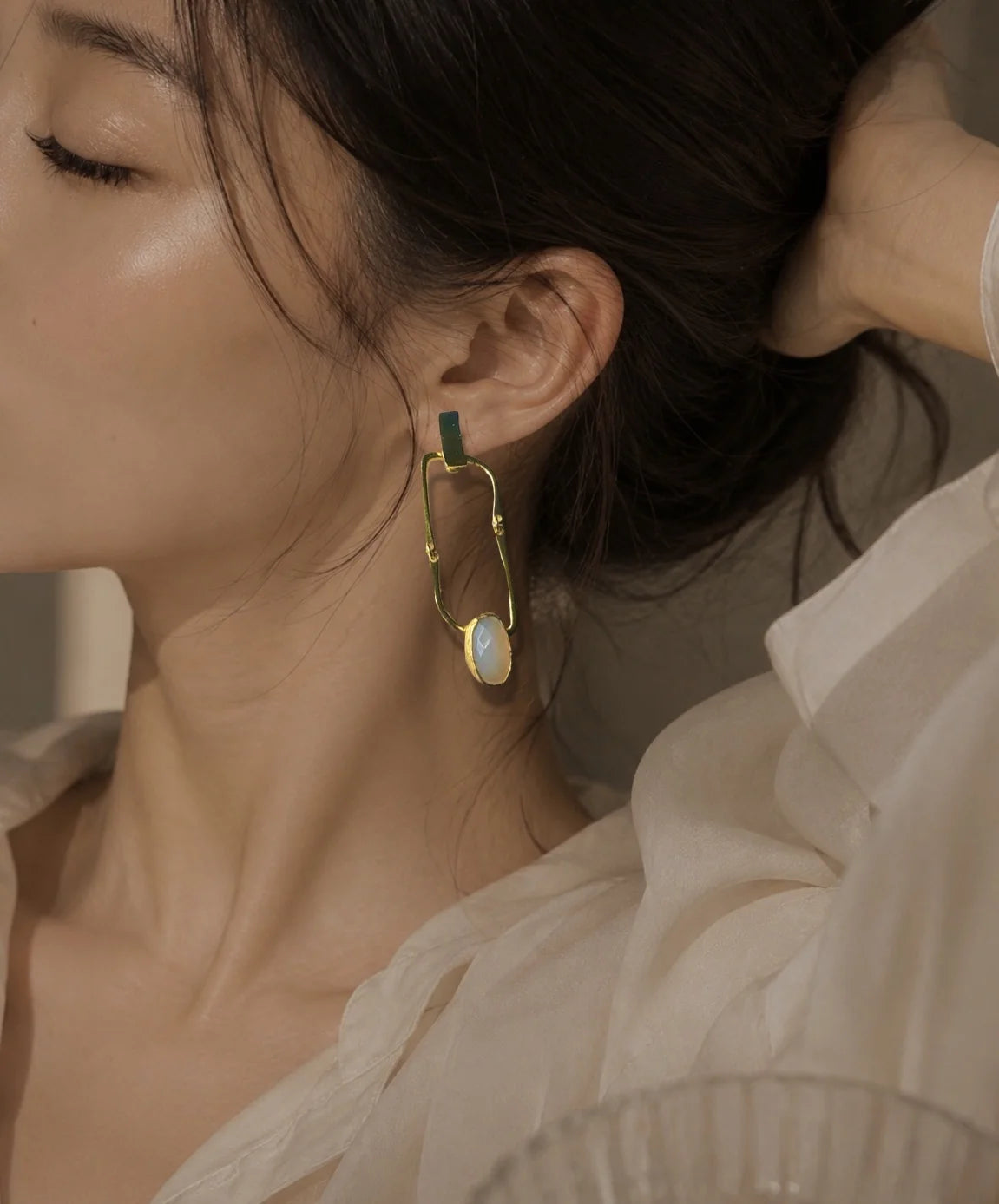 Model wearing handmade 21K gold-plated geometric drop earrings with white chalcedony gemstone by Bebek Jewels