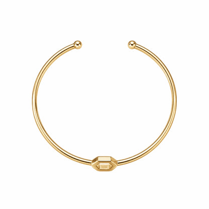 A gold-plated brass cuff bracelet with a central open hexagon design shown in aerial view on a plain white background.