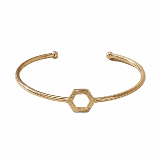 A gold-plated brass cuff bracelet with a central open hexagon design shown on a plain white background.