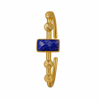 A gold-plated open cuff bangle bracelet featuring a rectangular blue lapis lazuli stone in the center, accented with four faceted gold accents on each side, on plain white background.