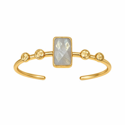Gold cuff bracelet featuring a rectangular faceted light gray labradorite gemstone in the center and four textured gold ball accents on each side of the stone, set on a white background.