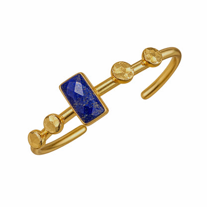 Gold bangle bracelet featuring a rectangular blue lapis lazuli stone and three round gold accents, set on a plain white background.