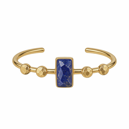 Gold cuff bracelet featuring a central rectangular blue lapis lazuli stone and three textured gold embellishings on each side, shown on a plain white background.