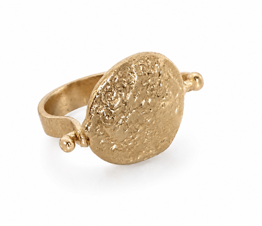 A gold signet coin flip ring with a textured oval face and a small round accent Facing the right 