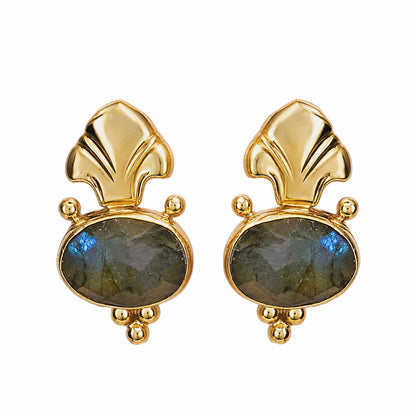 A pair of Fleur de lis gold stud earrings featuring oval labradorite stones in gray green, on a plain white background.