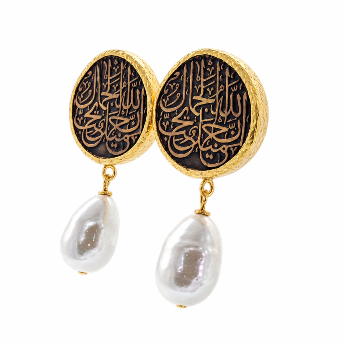 A pair of gold and black drop earrings featuring circular studs with Arabic calligraphy and dangling baroque white pearls on a white background facing left