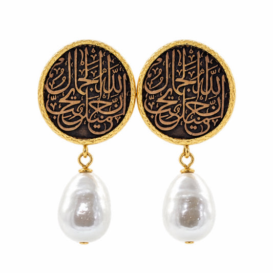 A pair of gold and black drop earrings featuring circular studs with Arabic calligraphy and dangling baroque white pearls, shown on a plain white background.