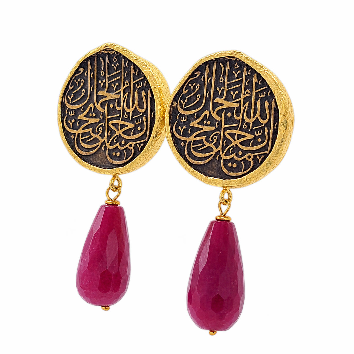 A pair of gold and black drop earrings featuring circular studs with Arabic calligraphy and dangling red ruby on a white background
Facing left 