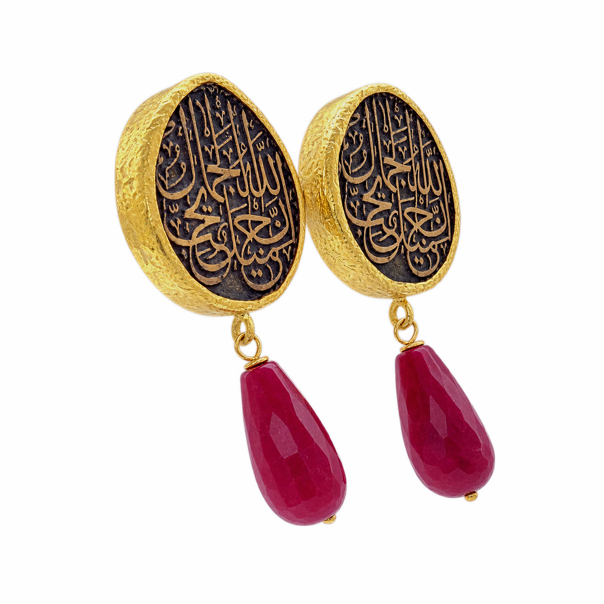 A pair of gold and black drop earrings featuring circular studs with Arabic calligraphy and dangling red ruby on a white background
Facing right