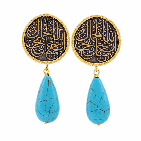 A pair of gold and black drop earrings featuring circular studs with Arabic calligraphy and dangling turquoise on a white background