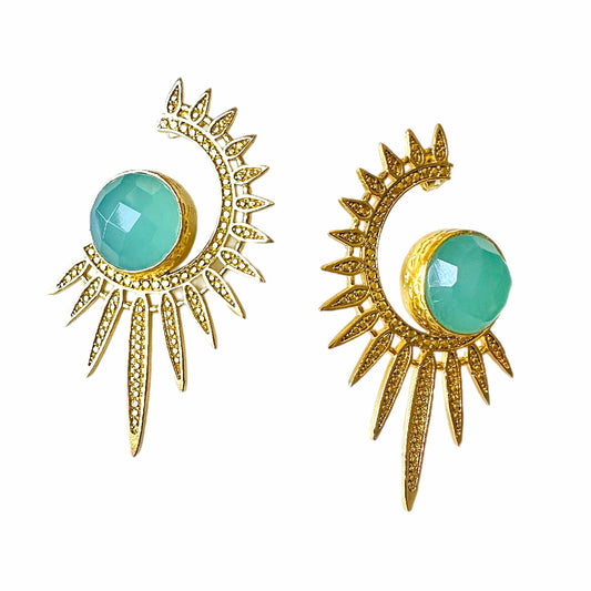 A pair of gold crescent moon and sunburst stud earrings with faceted aqua chalcedony gemstones, shown on a plain white background.