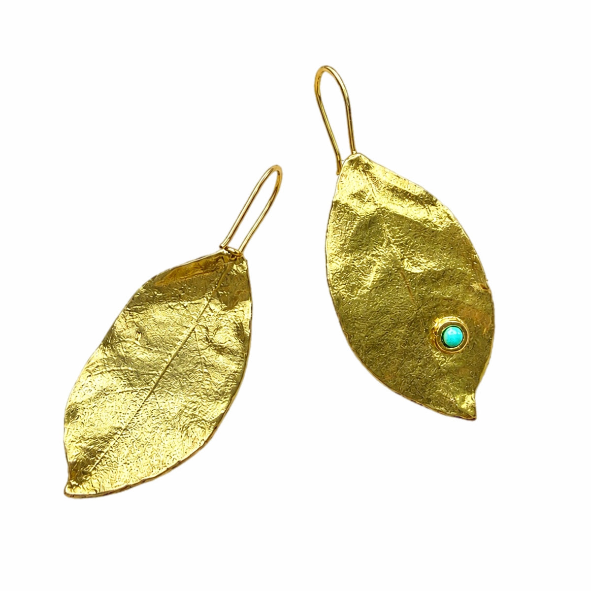 A pair of gold leaf drop earrings on a plain white background. One earring is a textured gold leaf with a simple wire hook, and the other is a larger textured gold leaf featuring a small round turquoise gemstone near the tip.