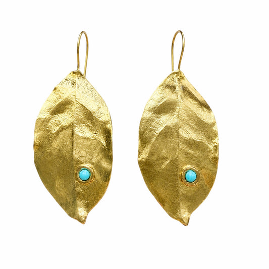 A pair of gold leaf-shaped drop earrings with a small round turquoise stone set near the bottom center, shown against a plain white background.