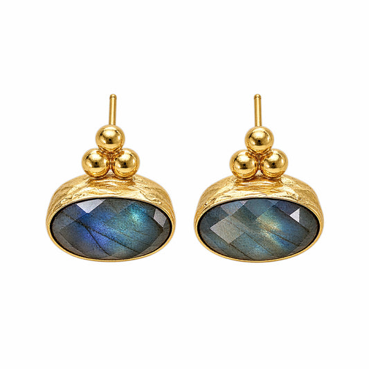 A pair of gold stud earrings featuring oval faceted labradorite stones with a blue-green iridescent sheen, set in a textured gold bezel with three small gold beads above.