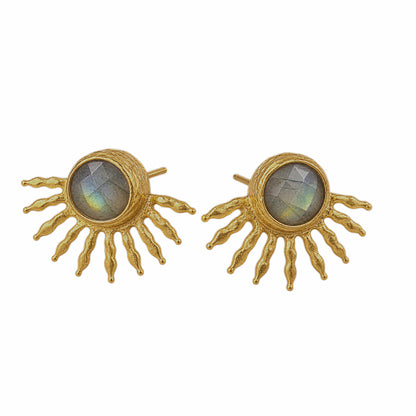 A pair of gold sunburst stud earrings with oval labradorite stones in the center, against a plain white background.