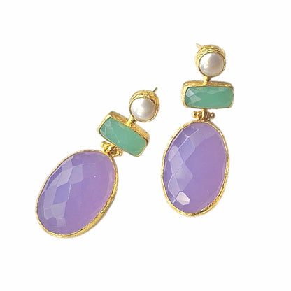 A pair of lilac quartz and aqua chalcedony dangle earrings with gold plating and pearl accents, displayed on a surface with a white backdrop