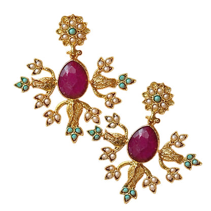 A pair of ornate gold-plated statement earrings featuring teardrop ruby central stones, surrounded by small pearl-like beads and turquoise green accents, on white background.