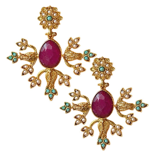 A pair of ornate gold-plated statement earrings featuring teardrop ruby central stones, surrounded by small pearl-like beads and turquoise green accents, set against a plain white background.