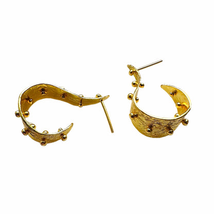 A pair of textured contemporary gold hoop earrings with small raised gold ball accents, on a white background.