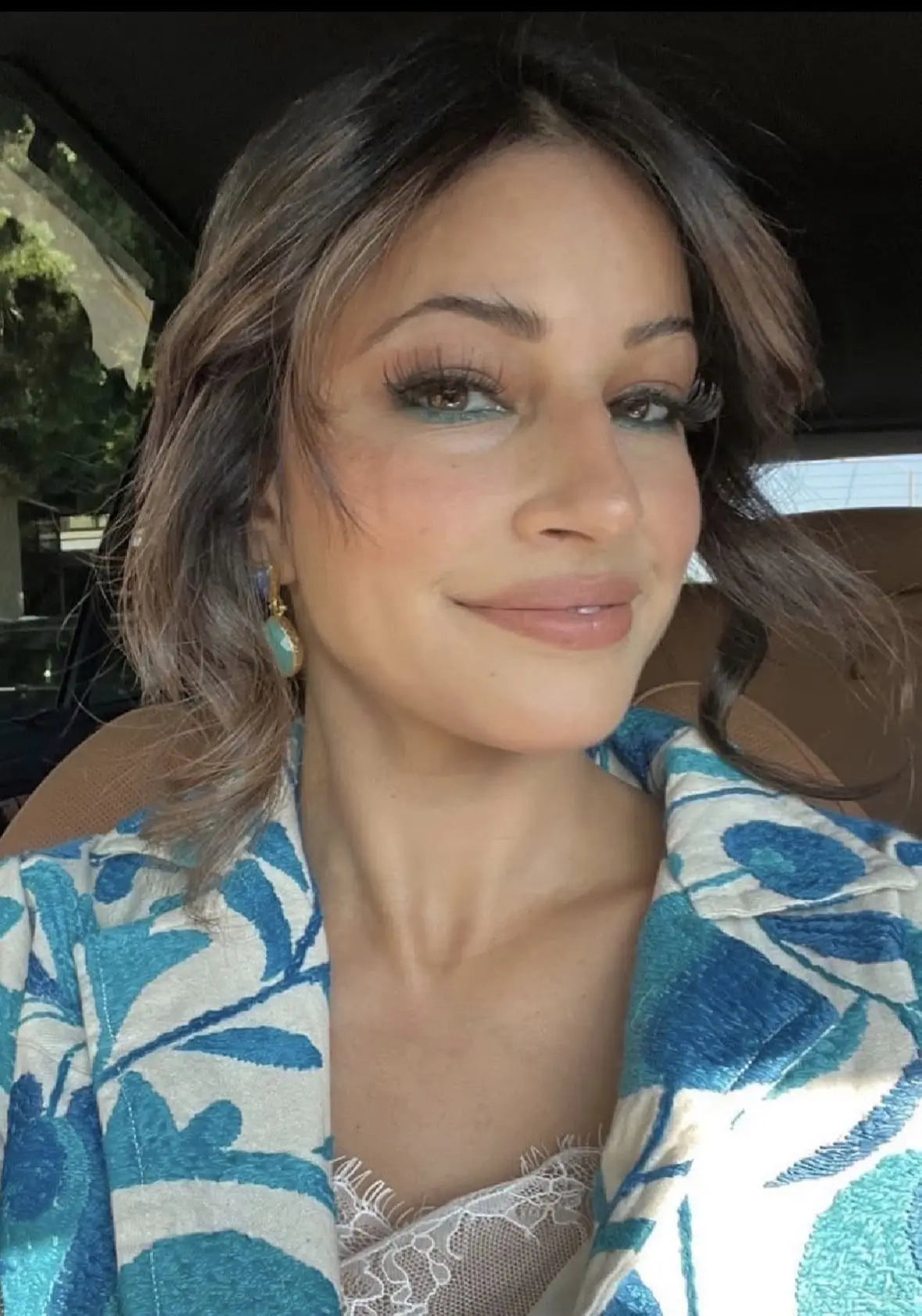 Hollywood actor Richa Moorjani wears handmade sustainable gold-plated lapis lazuli and Aqua Chalcedony drop earrings while sitting in car 