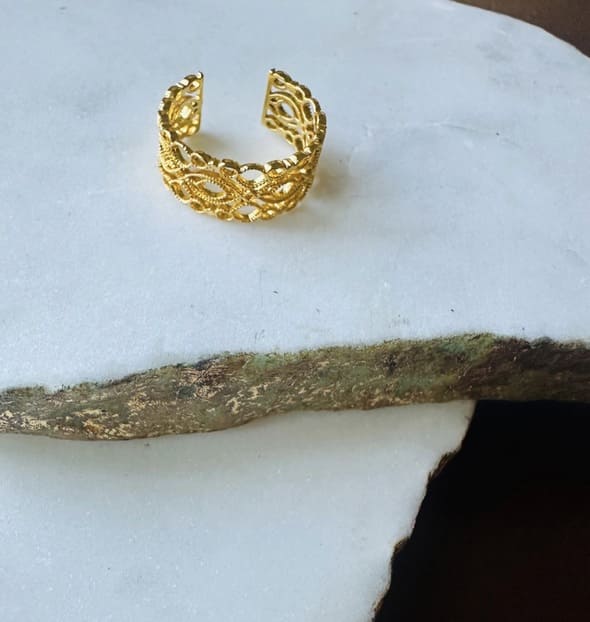 Gold-plated lace ring with intricate design on a white surface