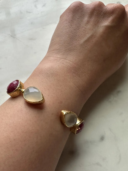 Arm wearing artisanal Gold bracelet with Ruby gemstones on a wrist against a marble background