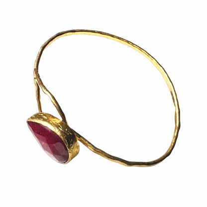 Artisanal Gold-plated hammer-finished bracelet with a red ruby gemstone on white surface