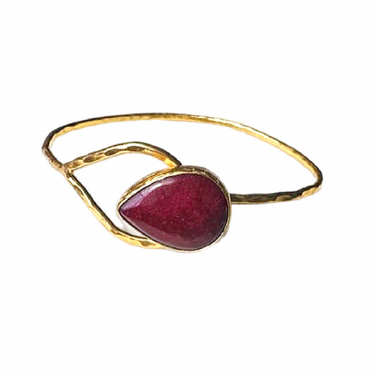 Artisanal Gold-plated hammer-finished bracelet with a red ruby gemstone on a white surface