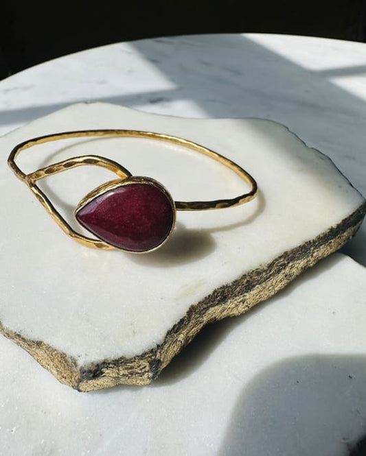 Artisanal Gold-plated hammer-finished bracelet with a red ruby gemstone on a marble surface