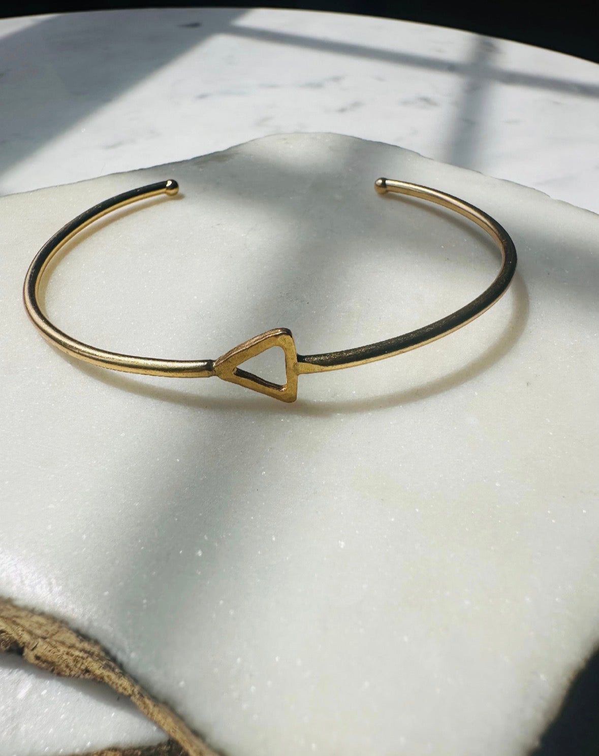 Gold-plated sustainable bracelet with a triangle charm on a white surface