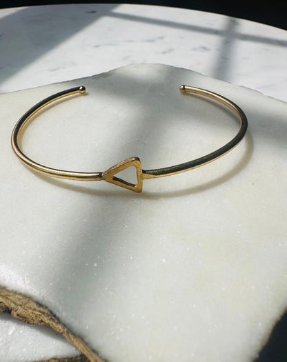 Gold-plated sustainable bracelet with a triangle charm on a white surface