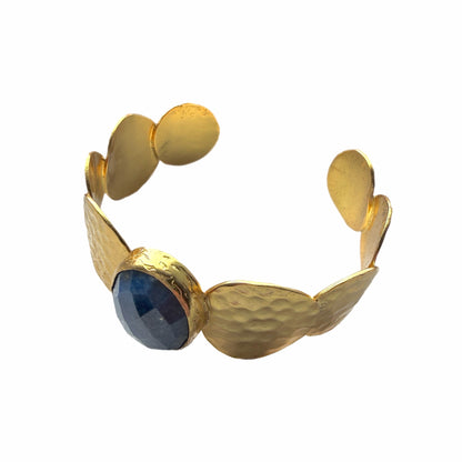 Gold-plated artisanal bracelet with a central blue lapis lazuli gemstone on a white background-facing-left