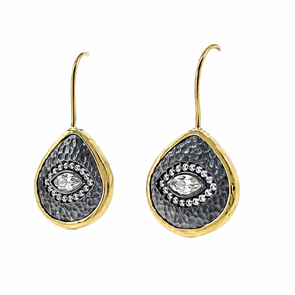 A pair of gold and dark silver teardrop-shaped drop earrings with a hammered gold finish, a textured center, and a central clear zircon evil  eye gemstone surrounded by small clear stones, shown on white background.