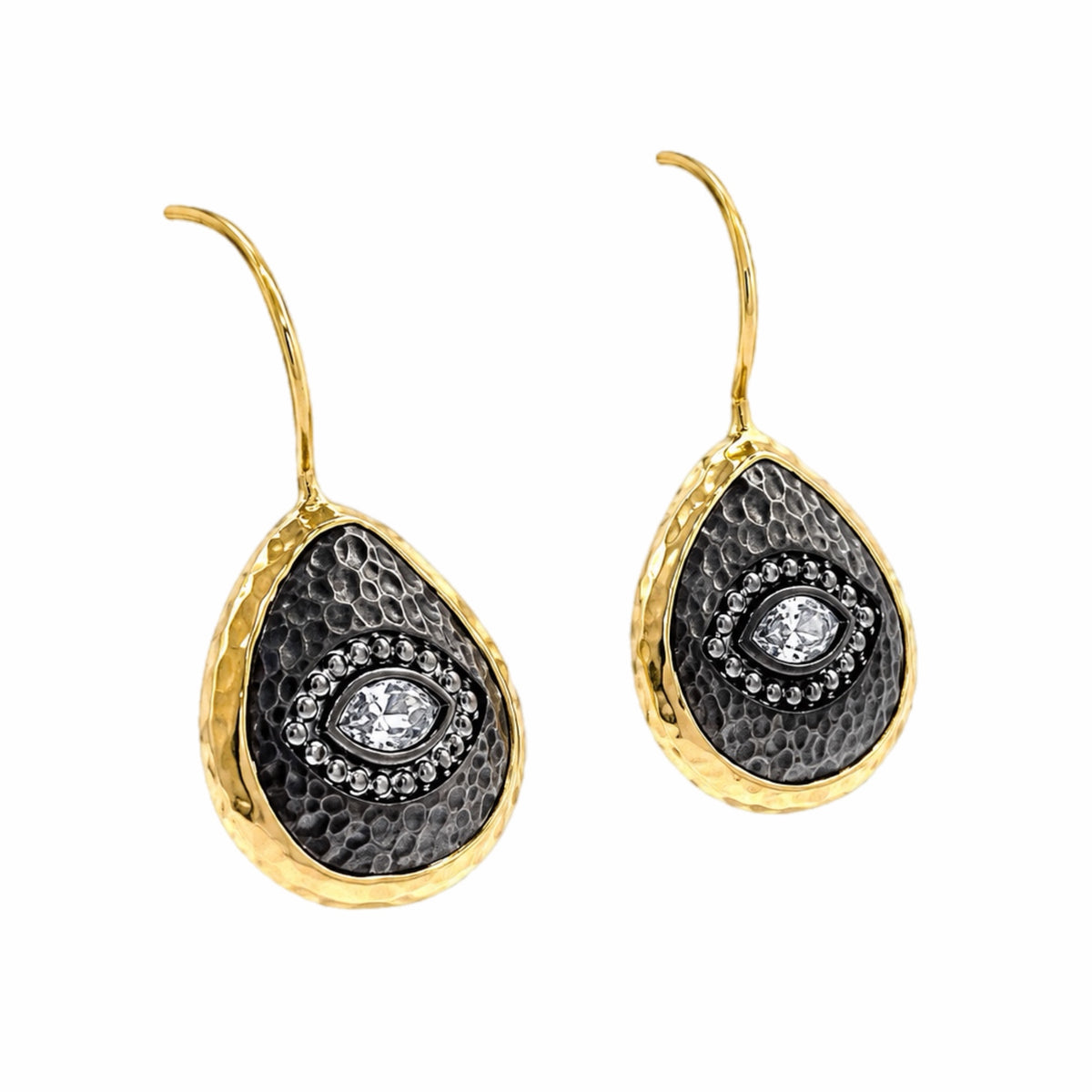 A pair of gold and dark silver teardrop-shaped drop earrings with a hammered gold finish, a textured center, and a central clear zircon evil  eye gemstone surrounded by small clear stones, shown on a plain white background.