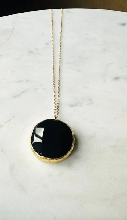 Artisanal sustainable round onyx pendant Necklace with long gold-plated chain on a marble surface