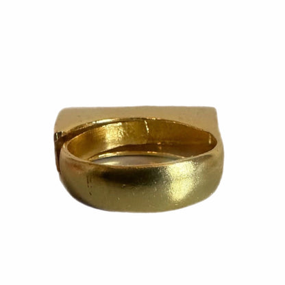 Back side of A gold-plated bar ring with Arabic calligraphy engraved on it, displayed on a white surface.