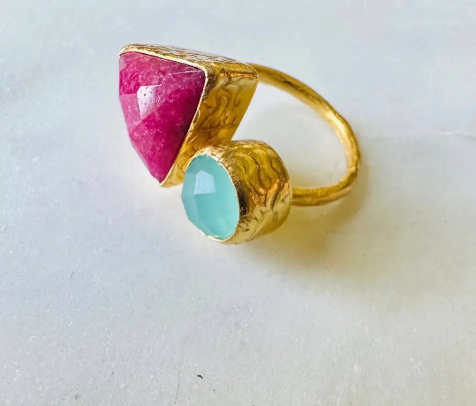 Stunning artisanal gemstone gold-plated gemstone ring with triangular ruby and round aqua chalcedony facing left against white background 