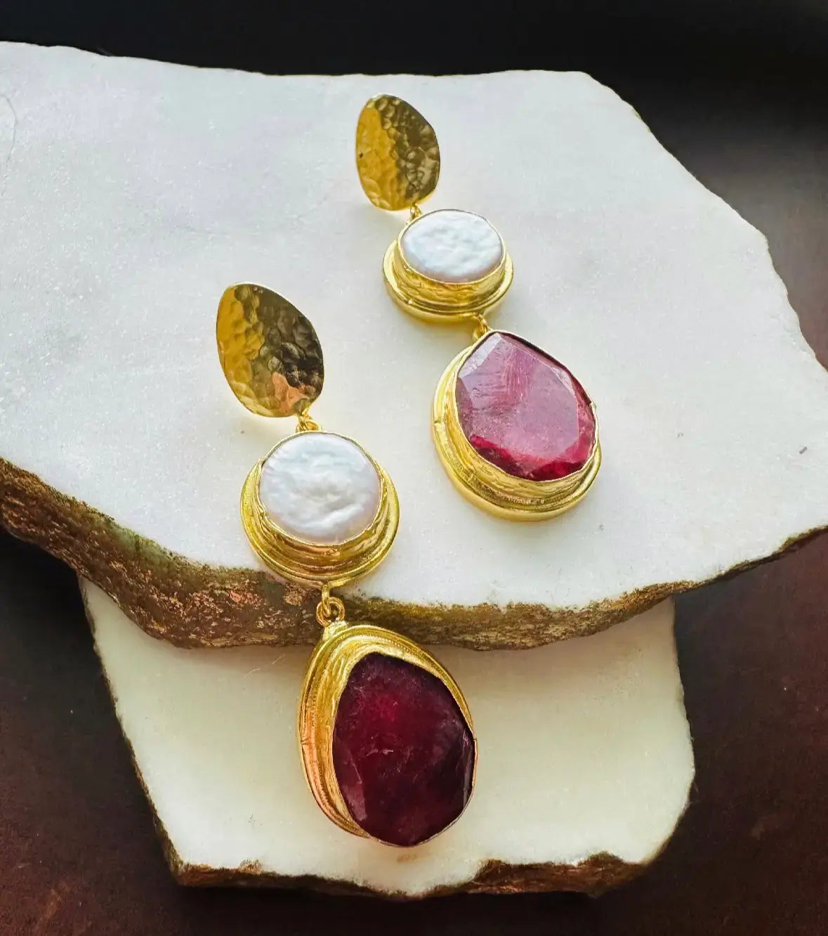 Elegant handmade gold-plated ruby and flat pearl dangle earrings on a white surface 