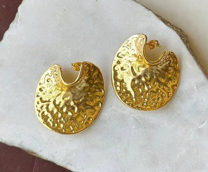 Gold-plated artisanal contemporary bold statement earrings on a white stone surface