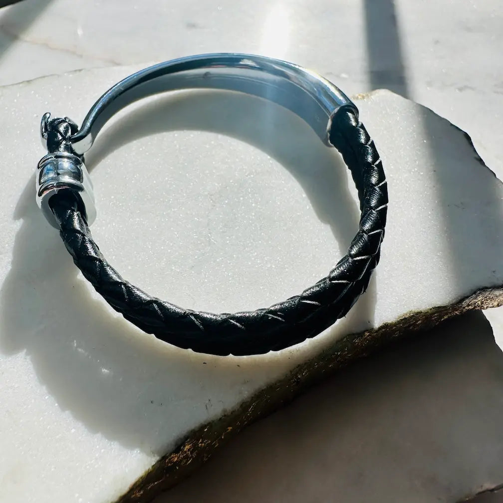 Handmade men’s Black braided leather bracelet with silver clasp on a white stone surface