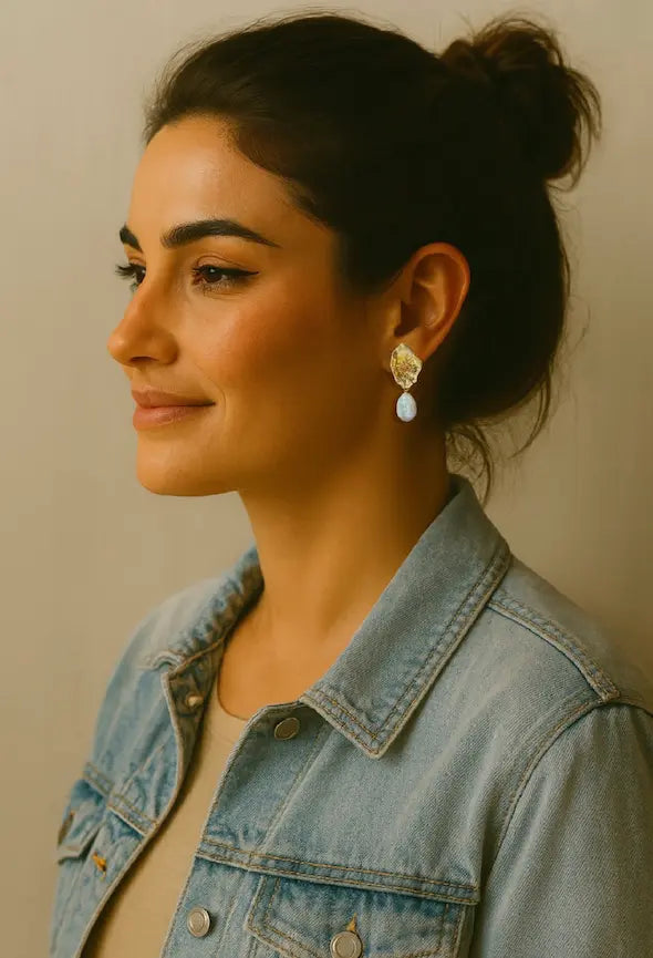 Woman wearing a denim jacket with a neutral background wearing handmade sustainable gold-plated flower and Baroque pearl earrings