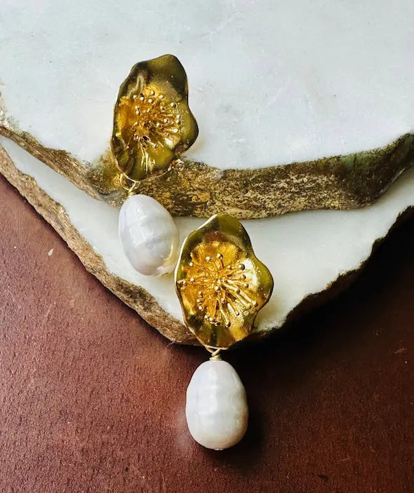 Sustainable Parisian inspired handmade gold-played gold flowe and Baroque pearl earrings on a marble surface