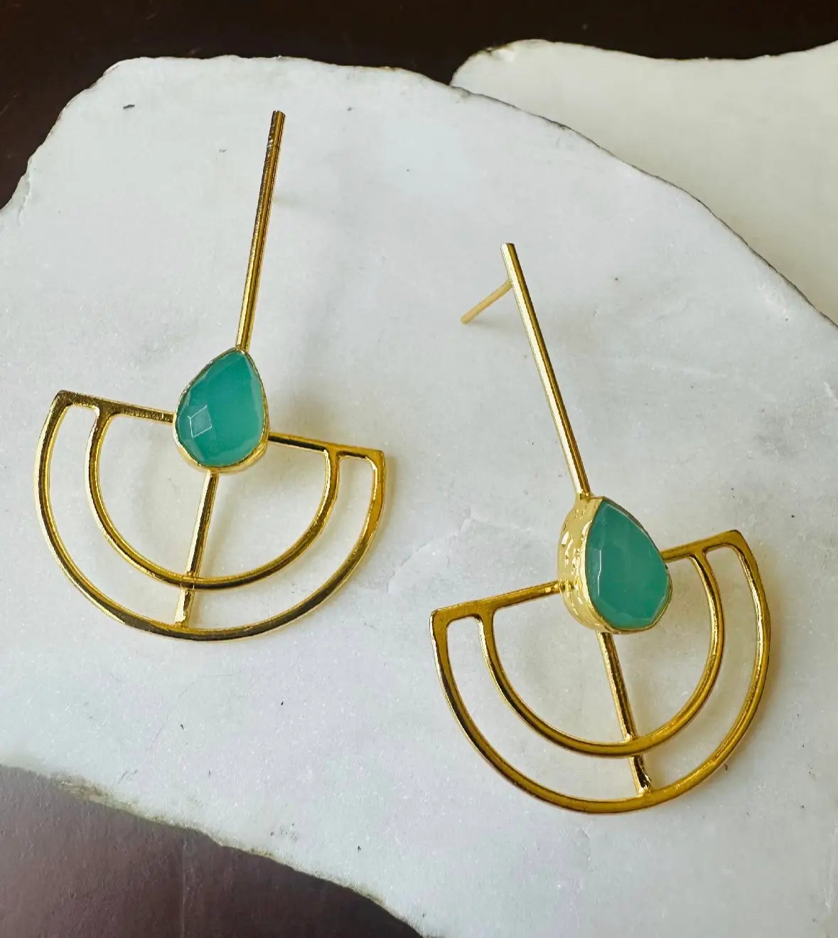 Gold-plated handmade sustainable Aqua Chalcedony earrings with green teardrop stones on a white stone