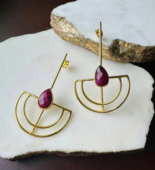 Gold-plated artisanal sustainable contemporary long geometric earrings with Ruby on a white stone surface